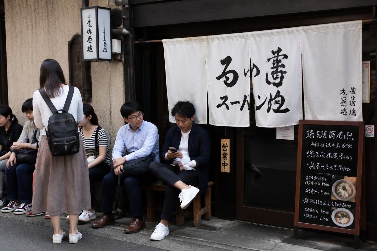 店舗の前でスマートフォンを見ながら順番を待つお客様